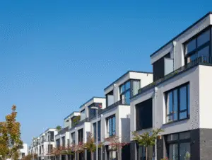 Row of modern townhouses with large windows and balconies under a clear blue sky.