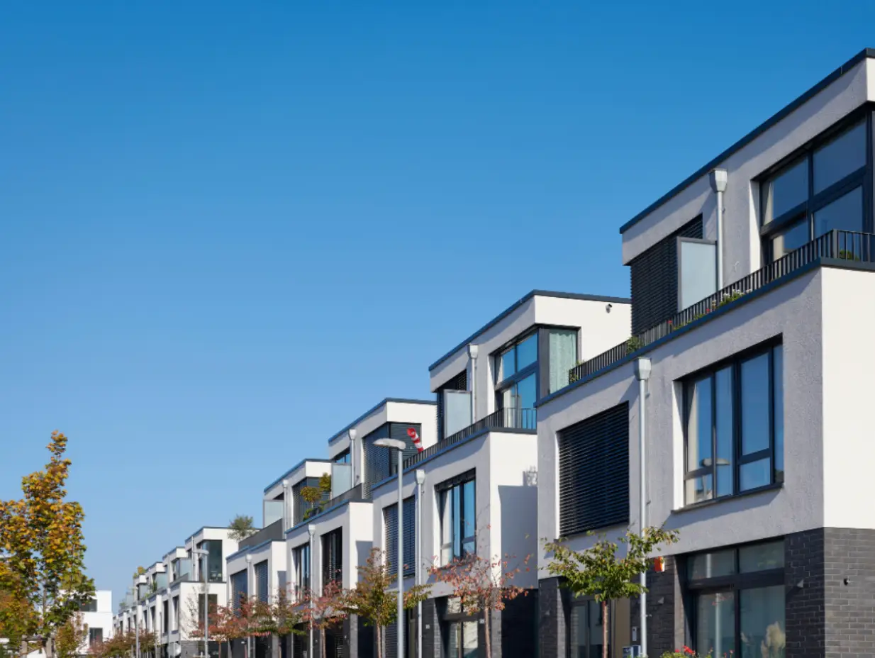 Row of modern townhouses with large windows and balconies under a clear blue sky.